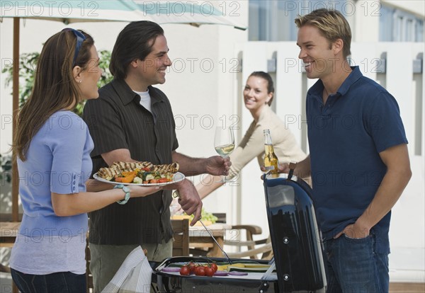 Couples barbecuing on patio.