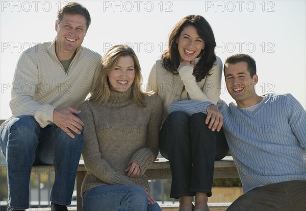 Portrait of couples sitting on outdoor bench.