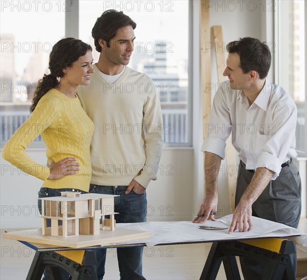 Architect presenting blueprints to couple.