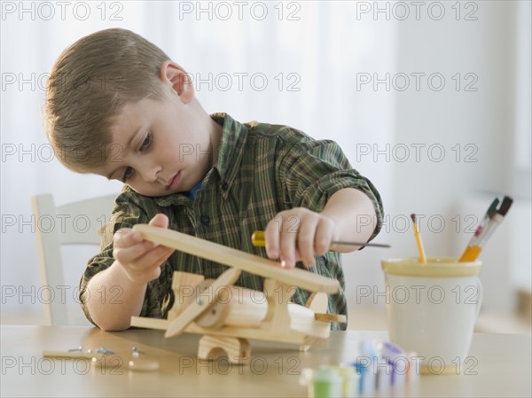 Boy building wooden airplane model.