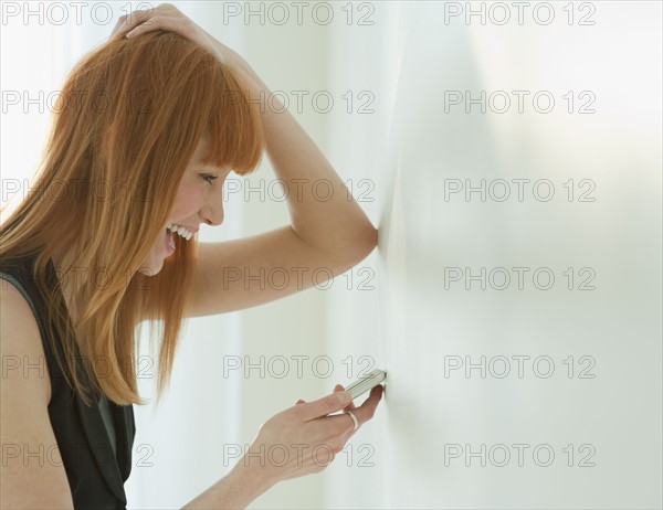 Woman laughing at cell phone.