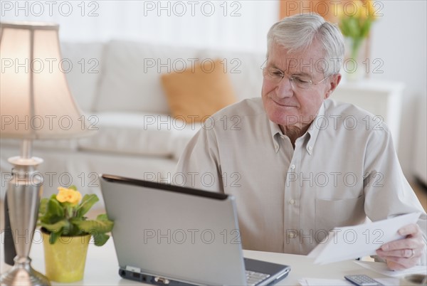 Senior man paying bills online.