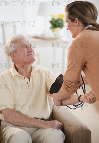 Nurse taking senior man’s blood pressure.