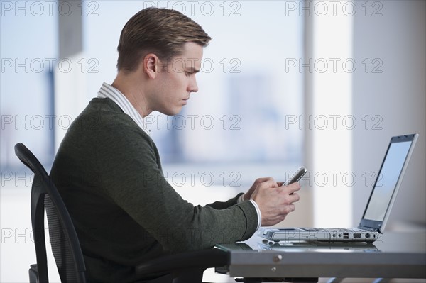 Businessman text messaging in office.