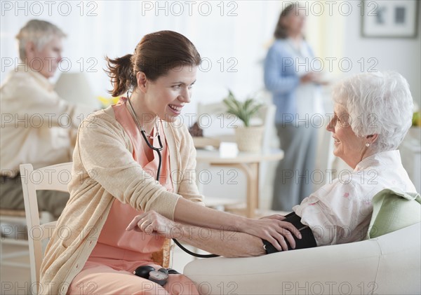 Nurse taking senior woman’s blood pressure.