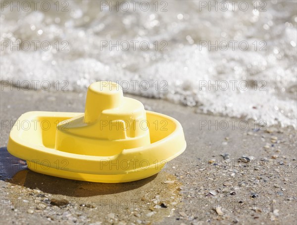 Toy boat on beach. Photographe : Jamie Grill