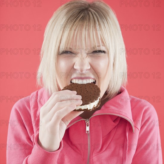 Woman eating ice cream sandwich. Photographe : Jamie Grill