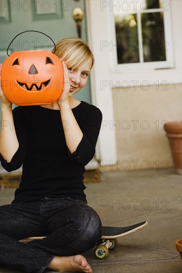 Girl holding plastic jack-o-lantern bucket. Photographe : Sarah M. Golonka