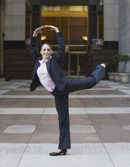 Businesswoman dancing in urban setting. Photographe : PT Images