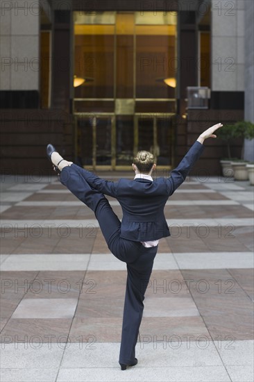 Businesswoman dancing in urban setting. Photographe : PT Images