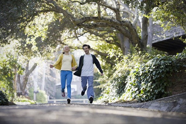 Young couple running on country road. Photographe : PT Images