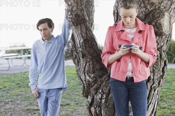 Boy watching girl text messaging outdoors. Photographe : PT Images