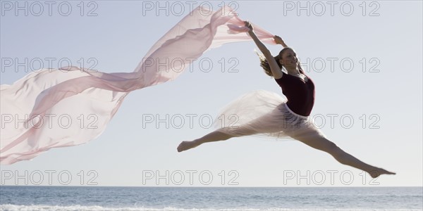 Dancer leaping on beach. Photographe : PT Images