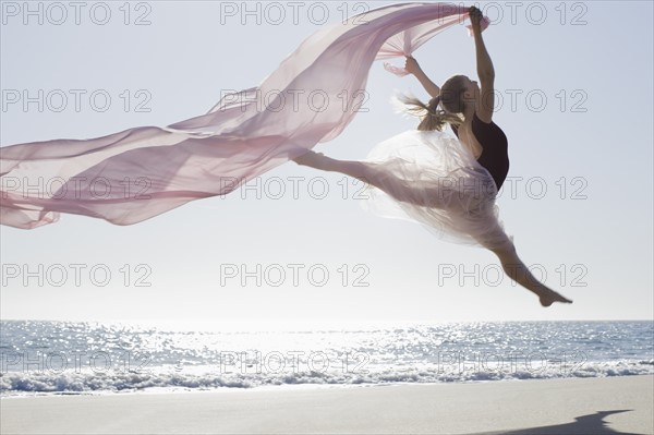 Dancer leaping on beach. Photographe : PT Images