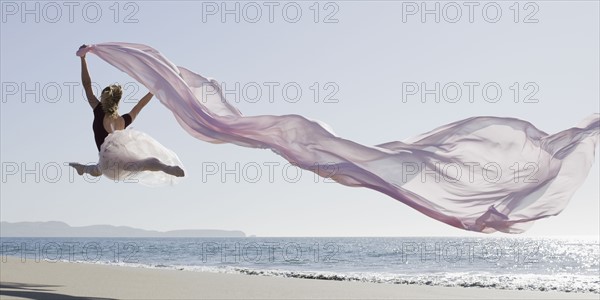 Dancer leaping on beach. Photographe : PT Images