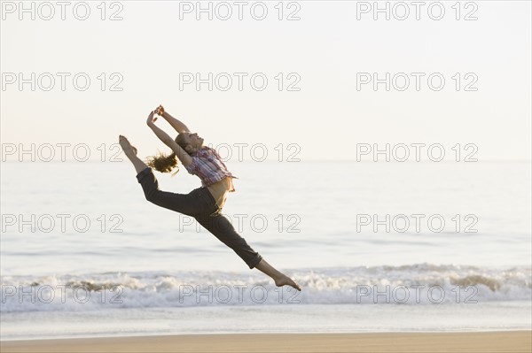 Woman dancing on beach. Photographe : PT Images