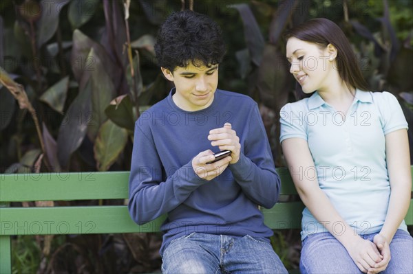 Young couple sitting on park bench. Photographe : PT Images