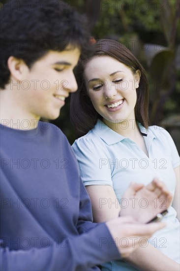 Young couple sitting on park bench. Photographe : PT Images