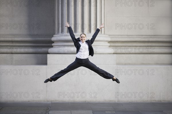 Businesswoman dancing in urban setting. Photographe : PT Images