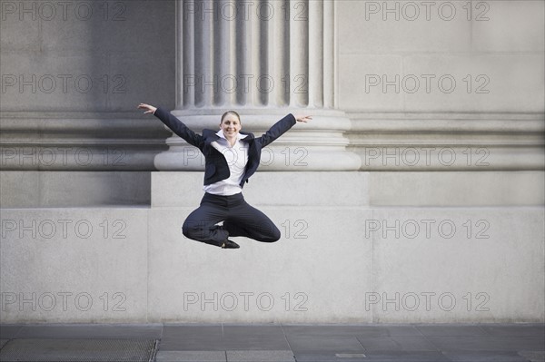 Businesswoman dancing in urban setting. Photographe : PT Images