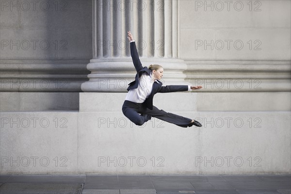 Businesswoman dancing in urban setting. Photographe : PT Images