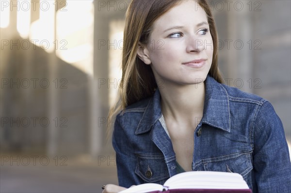 Young woman reading in urban setting. Photographe : PT Images