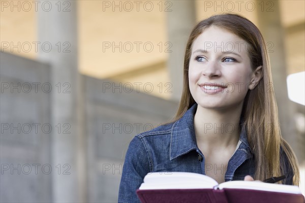 Young woman reading in urban setting. Photographe : PT Images