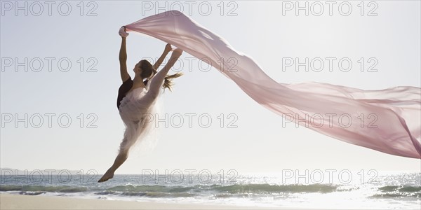 Dancer leaping on beach. Photographe : PT Images