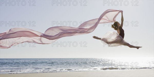 Dancer leaping on beach. Photographe : PT Images