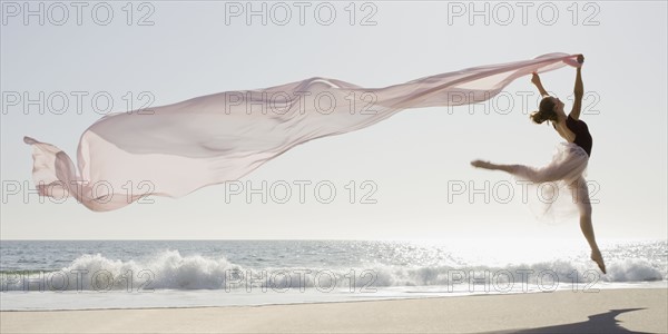 Dancer leaping on beach. Photographe : PT Images