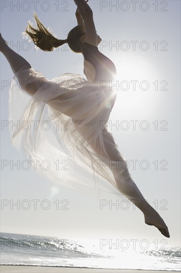 Dancer leaping on beach. Photographe : PT Images