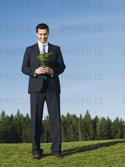 Businessman holding plant.
