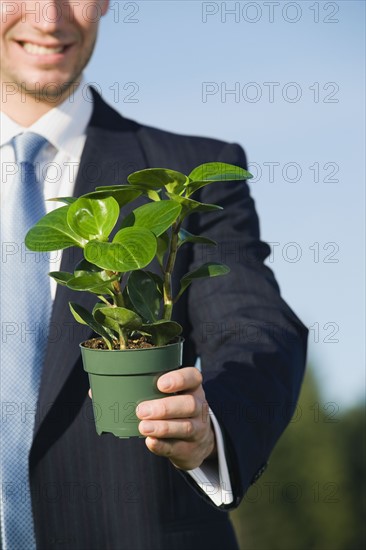 Businessman holding plant.