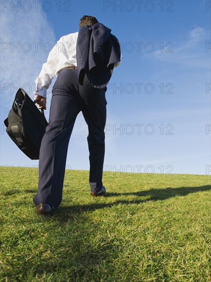 Businessman walking in grass.