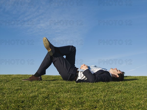 Businessman laying in grass.