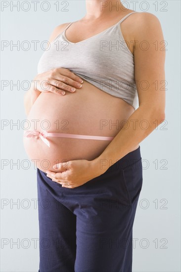 Pregnant woman’s belly wrapped in pink ribbon. Photographe : Jennifer L. Boggs