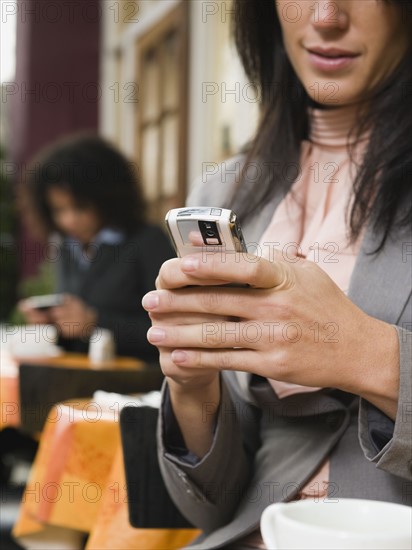 Businesswoman text messaging at outdoor cafe.