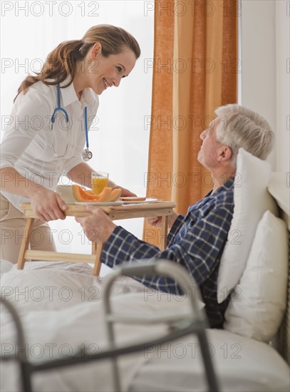 Nurse giving senior man breakfast.