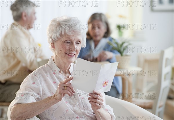 Senior woman reading greeting card.
