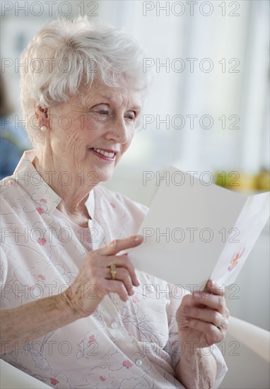 Senior woman reading greeting card.
