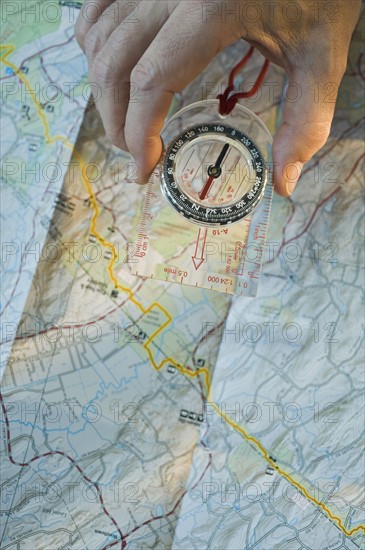 Man holding compass over map.