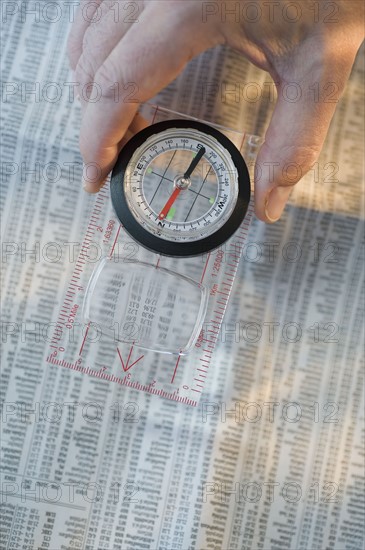 Man holding compass over stock pages.