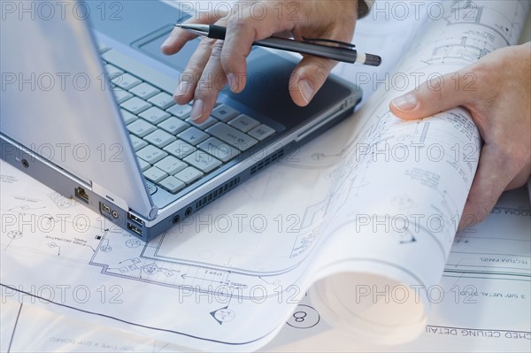 Architect with blueprints and laptop.