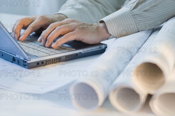 Architect with blueprints and laptop.