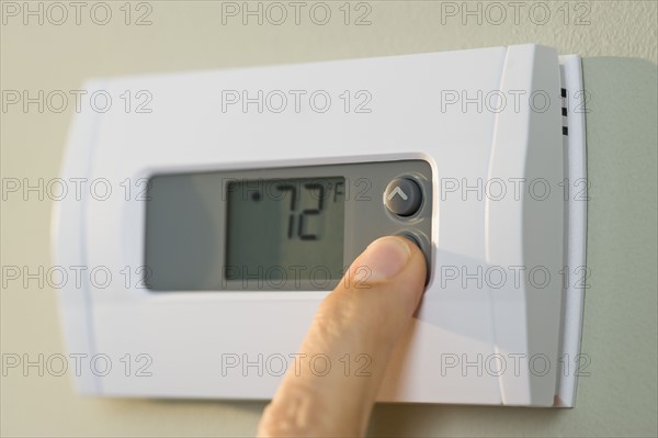 Man adjusting thermostat.