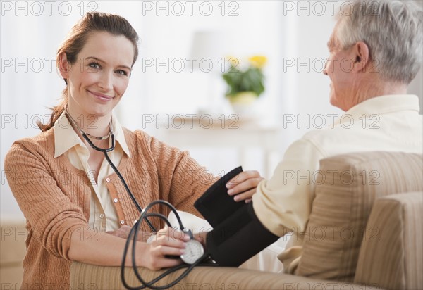 Nurse taking senior man’s blood pressure.