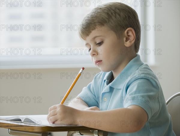 Boy writing in classroom.