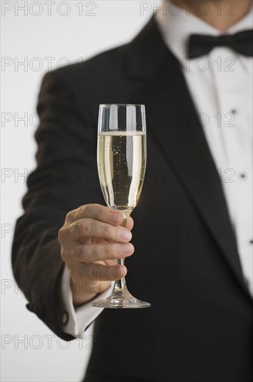 Man in tuxedo toasting with champagne.