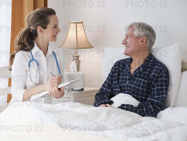 Nurse caring for senior man in bed.