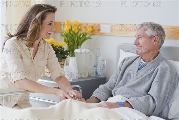 Daughter visiting senior father in hospital.